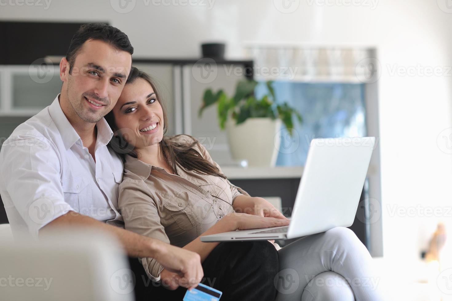 casal alegre relaxa e trabalha no computador portátil em casa moderna foto