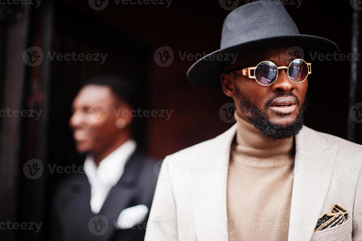 dois homens negros da moda. retrato elegante de modelos masculinos afro-americanos. usar terno, casaco e chapéu. foto