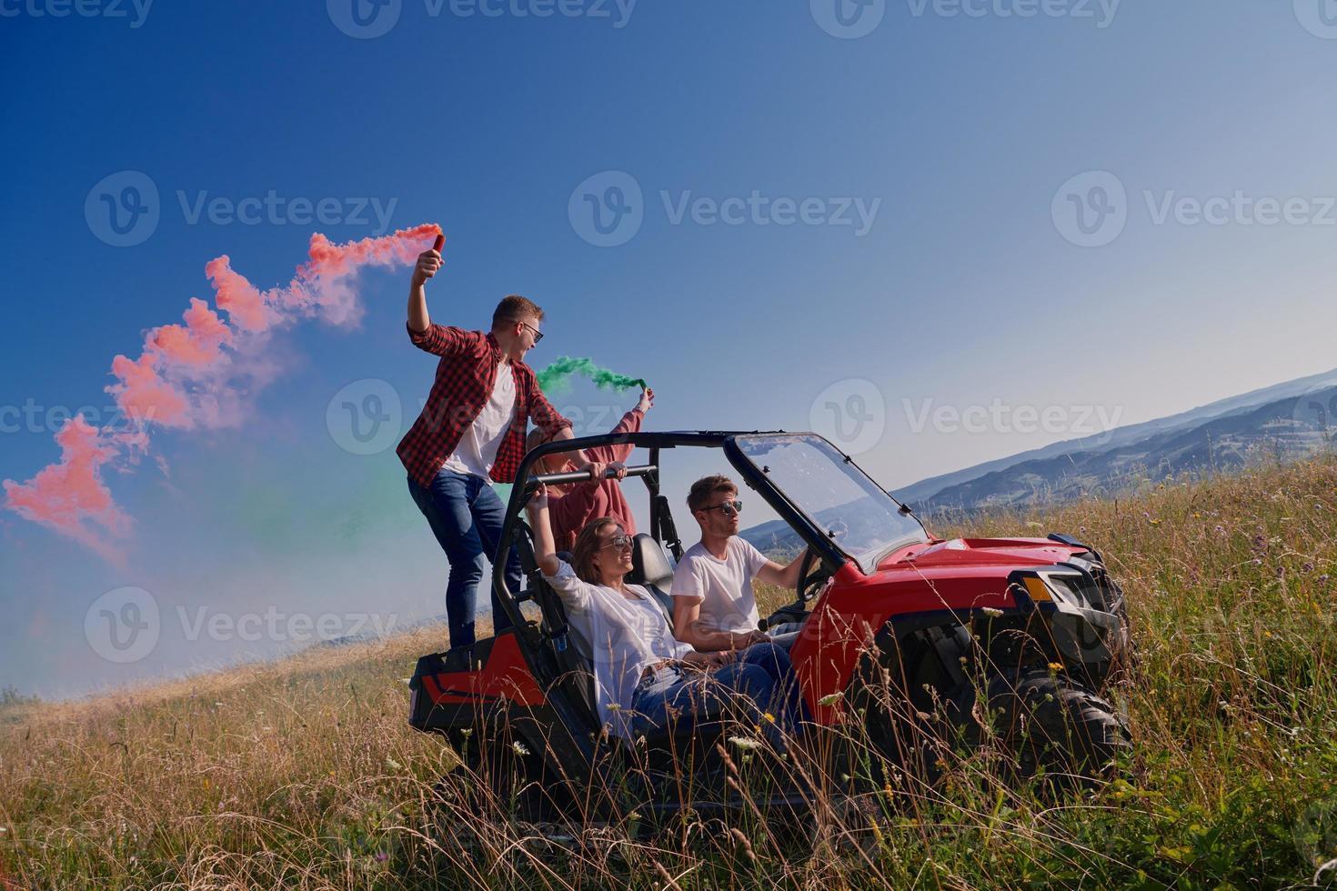 pessoas animadas se divertindo aproveitando um belo dia ensolarado segurando tochas coloridas enquanto dirigia um carro de buggy off road foto