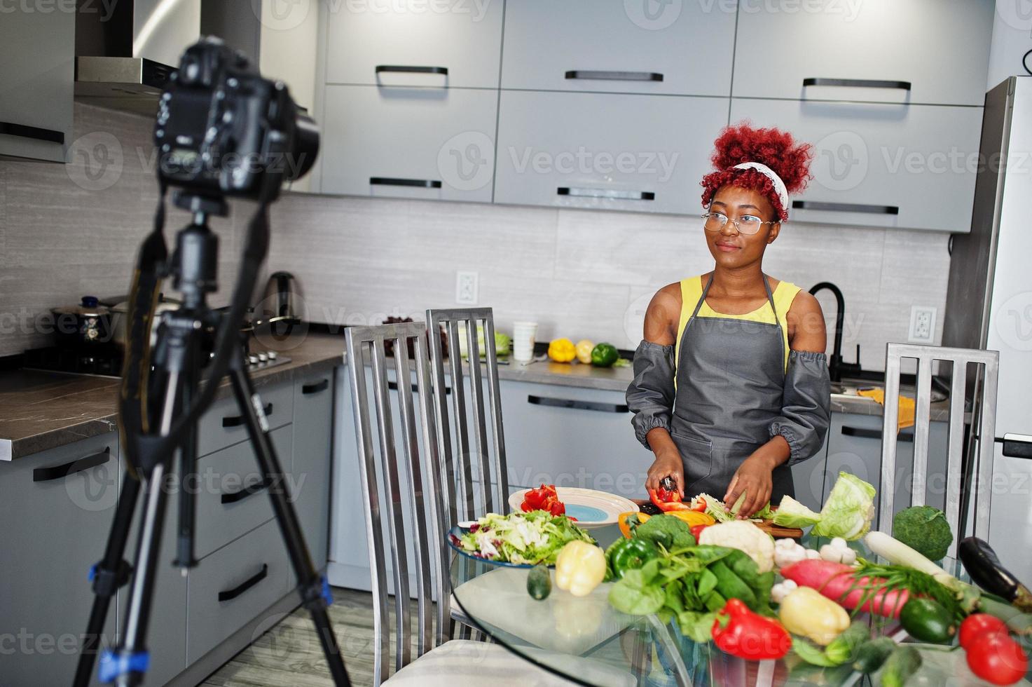 mulher afro-americana filmando sua transmissão de blog sobre comida saudável na cozinha de casa. foto