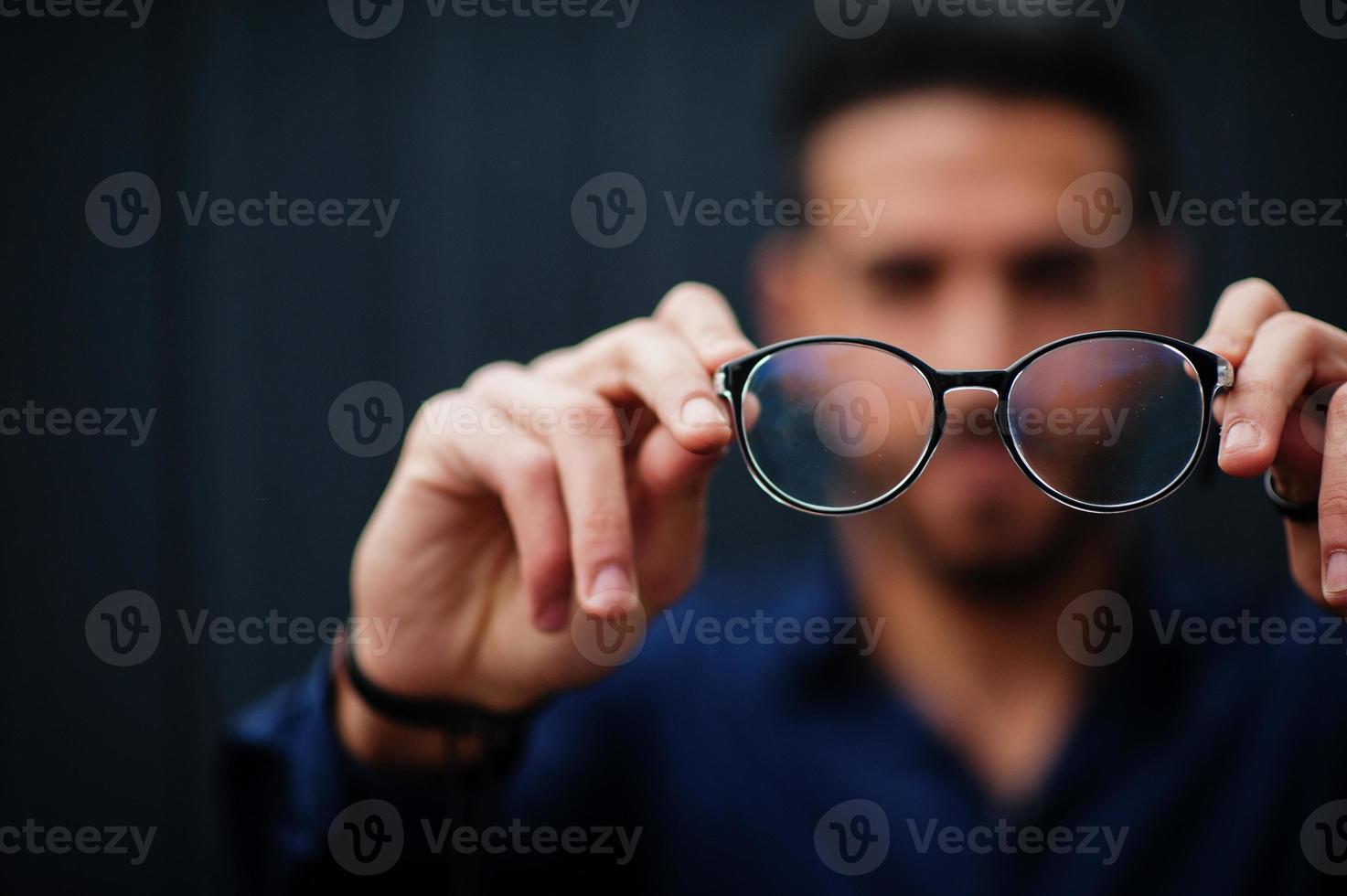 empresário do Oriente Médio usar camisa azul mostrar óculos de close-up, contra a parede de aço. foto