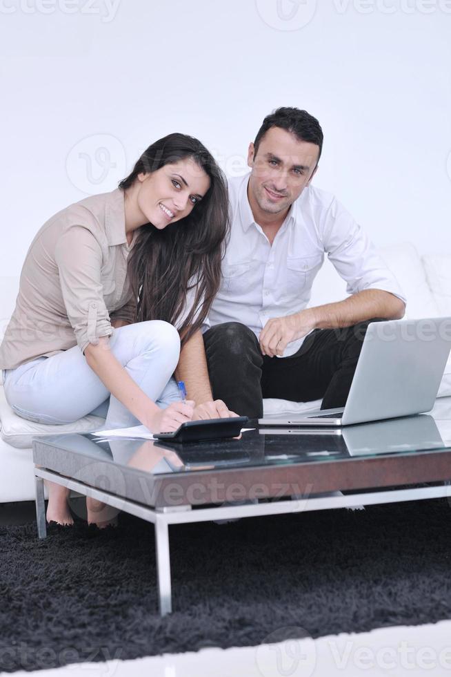 casal alegre relaxa e trabalha no computador portátil em casa moderna foto