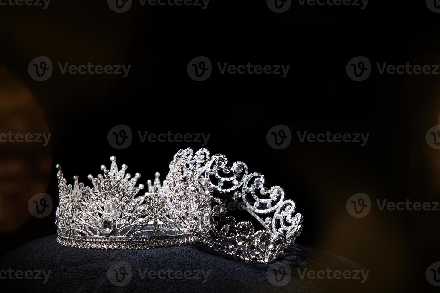 coroa de prata de diamante para concurso de beleza de concurso de miss, joias de tiara de cristal decoradas com pedras preciosas e fundo escuro abstrato em tecido de veludo preto, espaço de cópia de macro fotografia para logotipo de texto foto