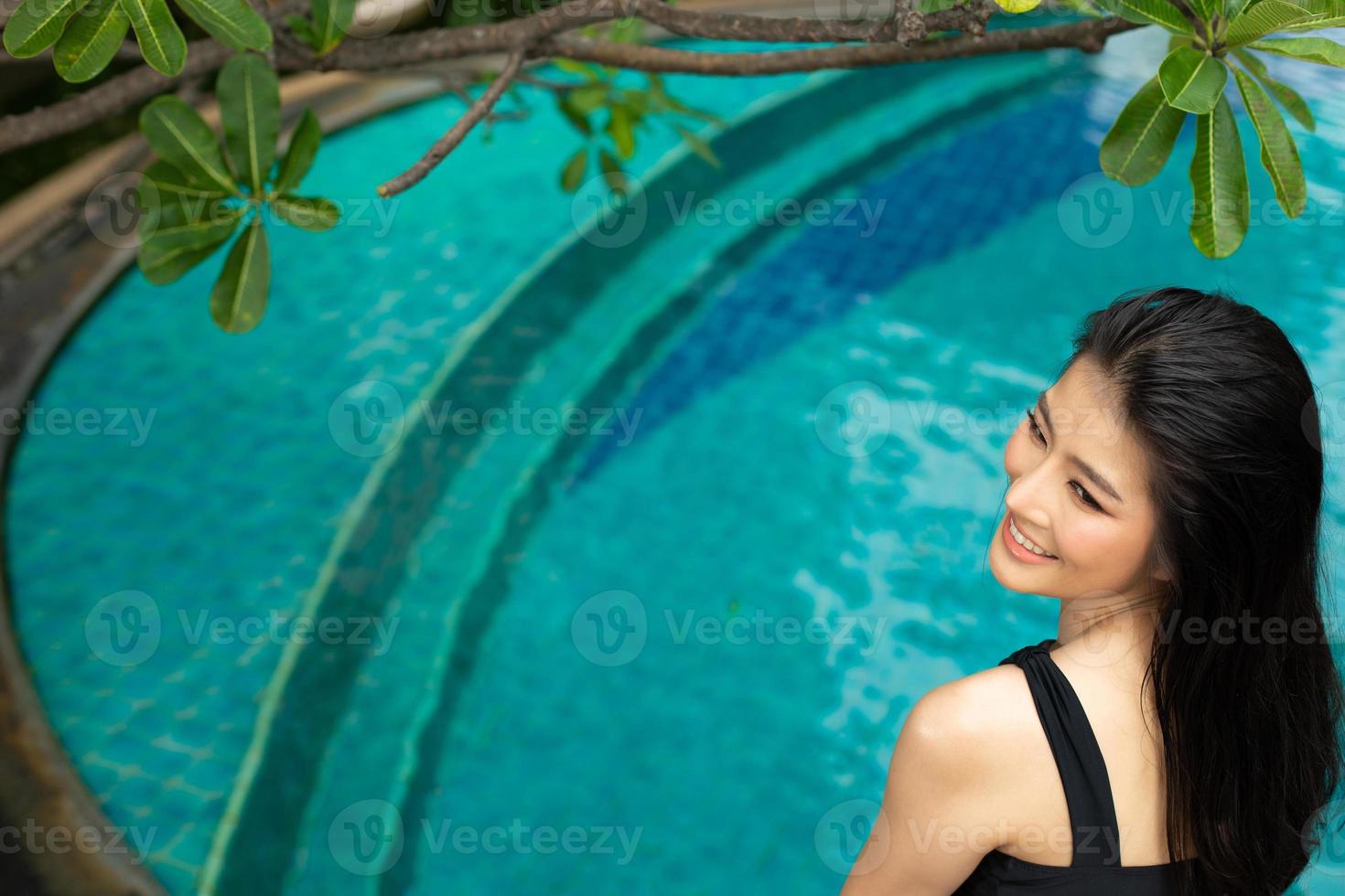 linda linda garota usa biquíni de maiô preto, mulher asiática relaxa na piscina azul no hotel spa resort em férias de férias de viagem, copie o espaço foto