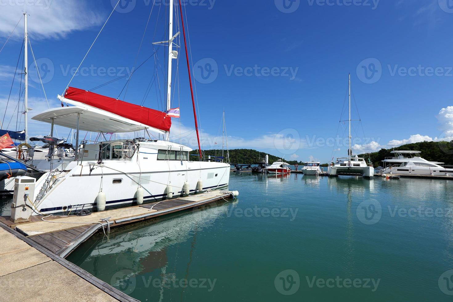 muitos iates de luxo flutuam no mar cristalino no clube marina bay, barco privado caro fica calmo no cais de ancoragem sob o céu azul de verão oceano verde foto