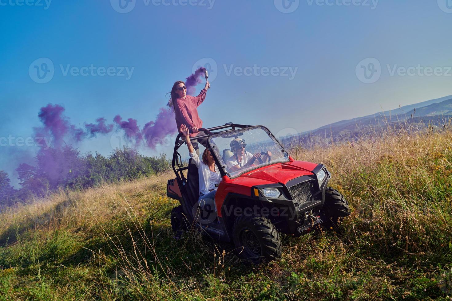 pessoas animadas se divertindo aproveitando um belo dia ensolarado segurando tochas coloridas enquanto dirigia um carro de buggy off road foto