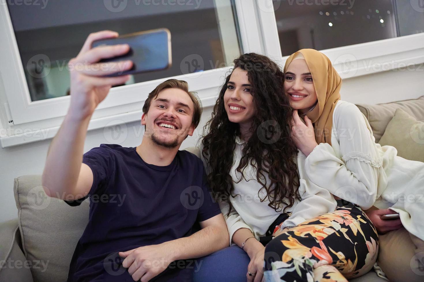 jovem feliz, muçulmanos tomando selfie em casa foto