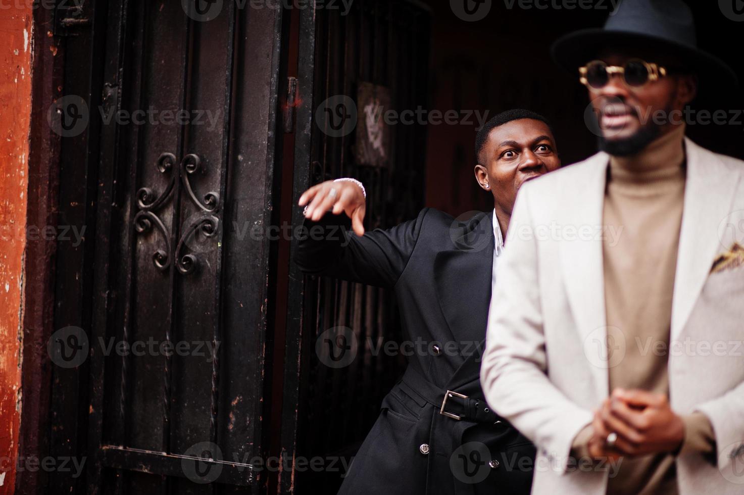 dois homens negros da moda. retrato elegante de modelos masculinos afro-americanos. usar terno, casaco e chapéu. foto