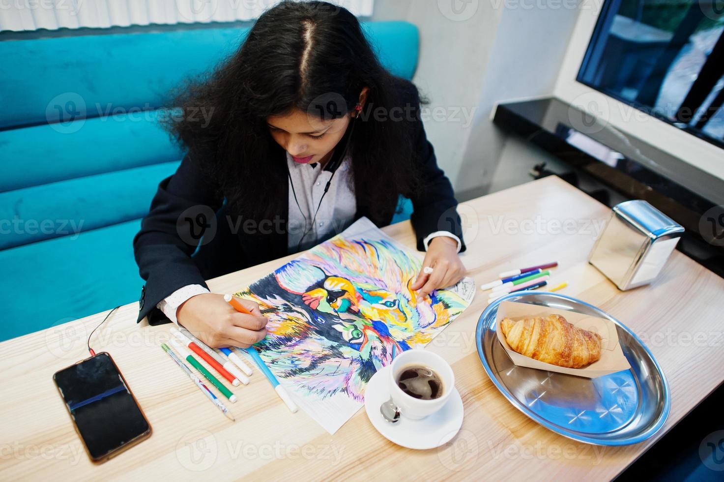 artista indiana mulher vestir imagem de pintura formal e ouvir música hindu de fones de ouvido, enquanto está sentado no café. foto