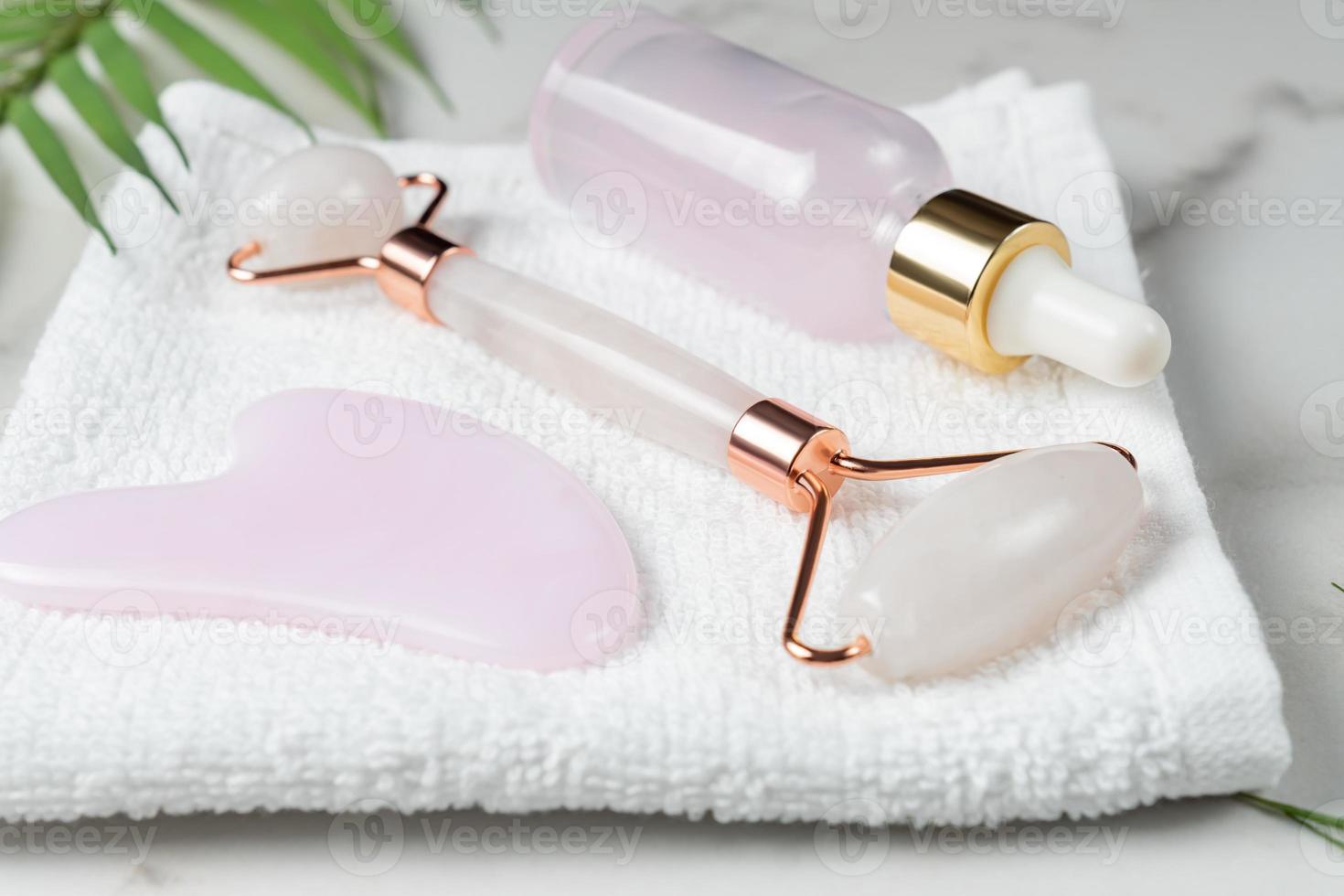 raspador de guasha massageador de rosto de rolo rosa. massageador facial de pedra jade para rosto e corpo com frasco conta-gotas de soro de beleza. conceito de moda na moda. cuidados anti-envelhecimento, lifting e tonificação em casa. foto