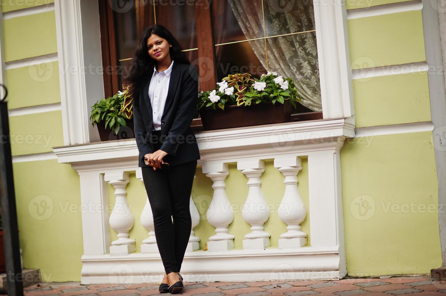 linda mulher indiana veste formal posando na rua com o celular nas mãos. foto