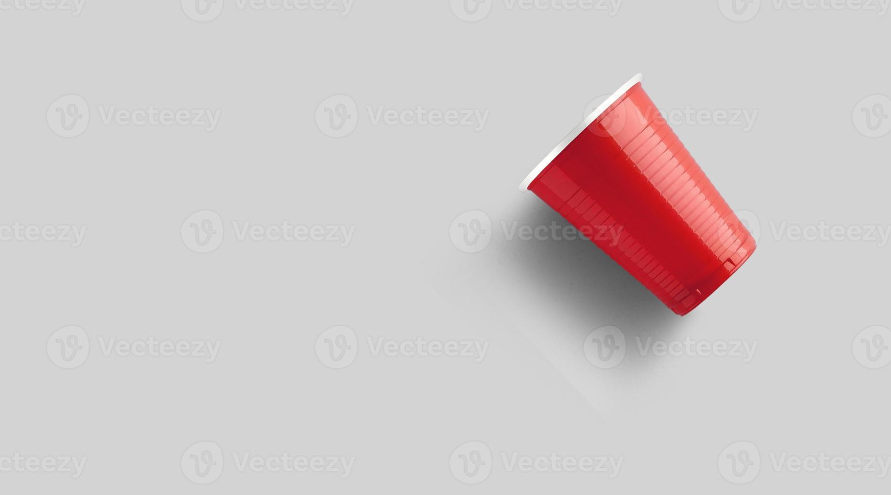 copo de plástico vermelho isolado em cinza. conceito de jogo de pong de cerveja foto