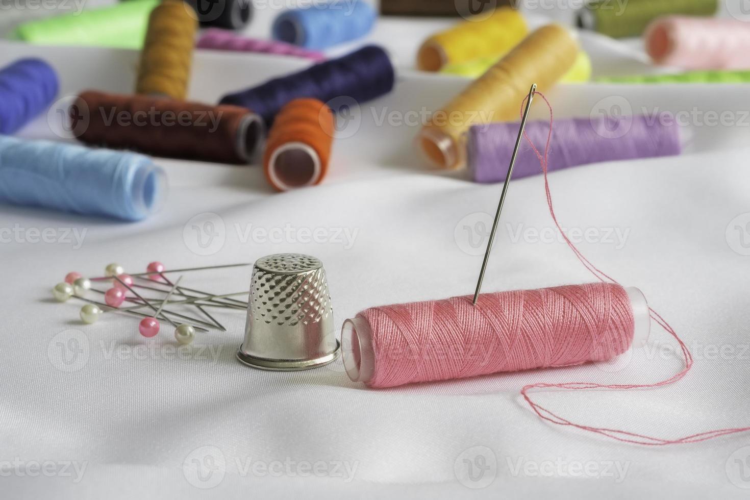 agulha, alfinetes, dedal e carretéis coloridos de linha foto