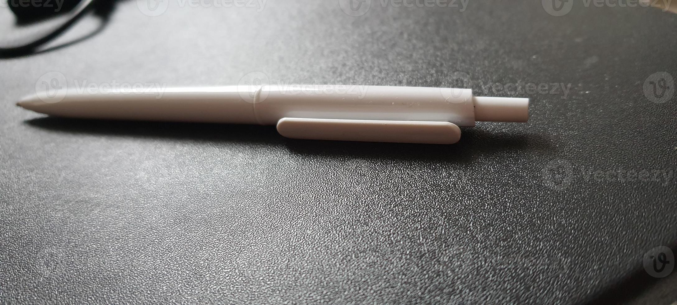 uma caneta branca em uma mesa preta. foto