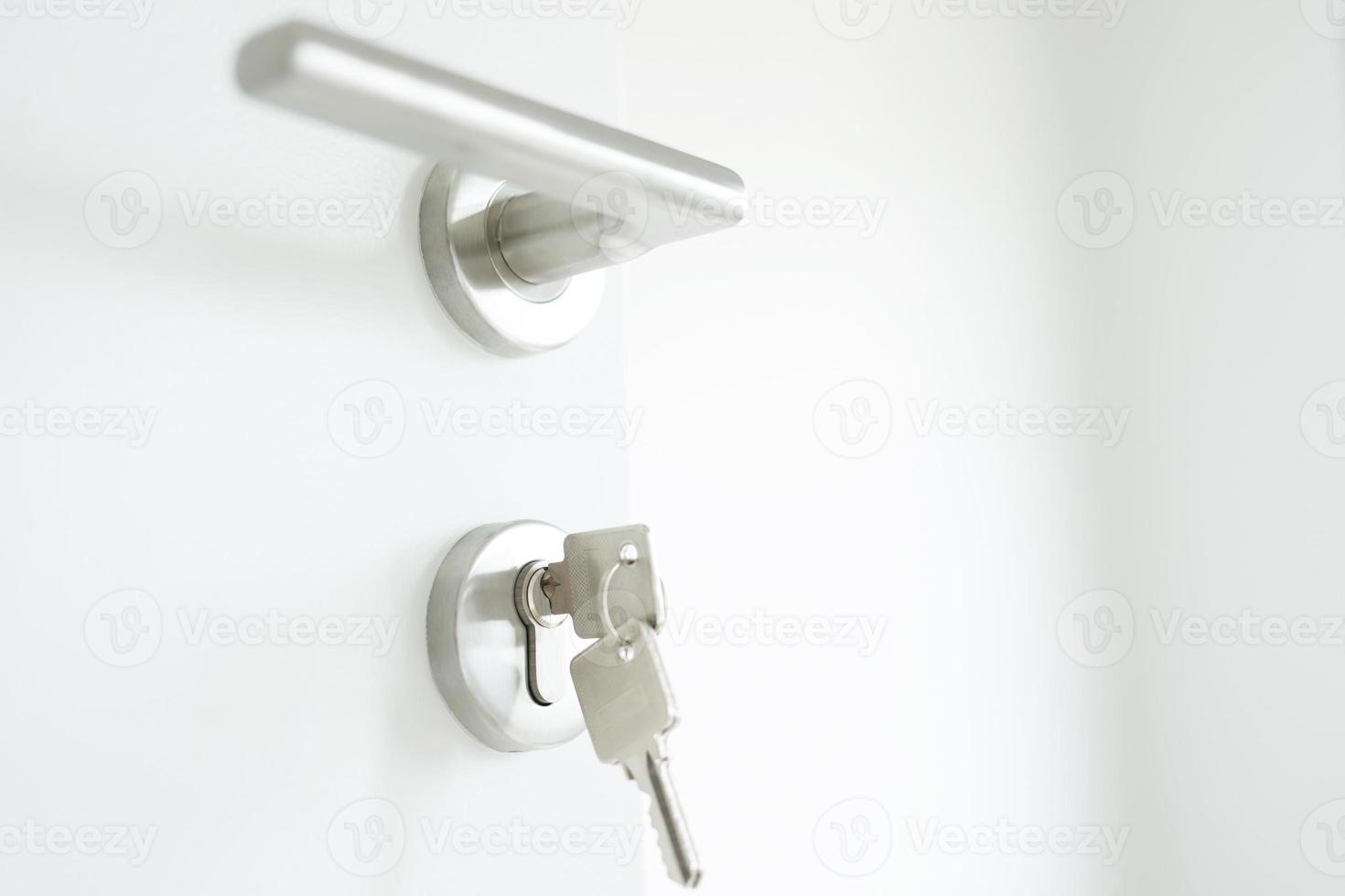 chave de casa no chaveiro em forma de casa chaveiro de prata na fechadura de uma porta. conceito para comprar habitação e apartamento de agente imobiliário. foto