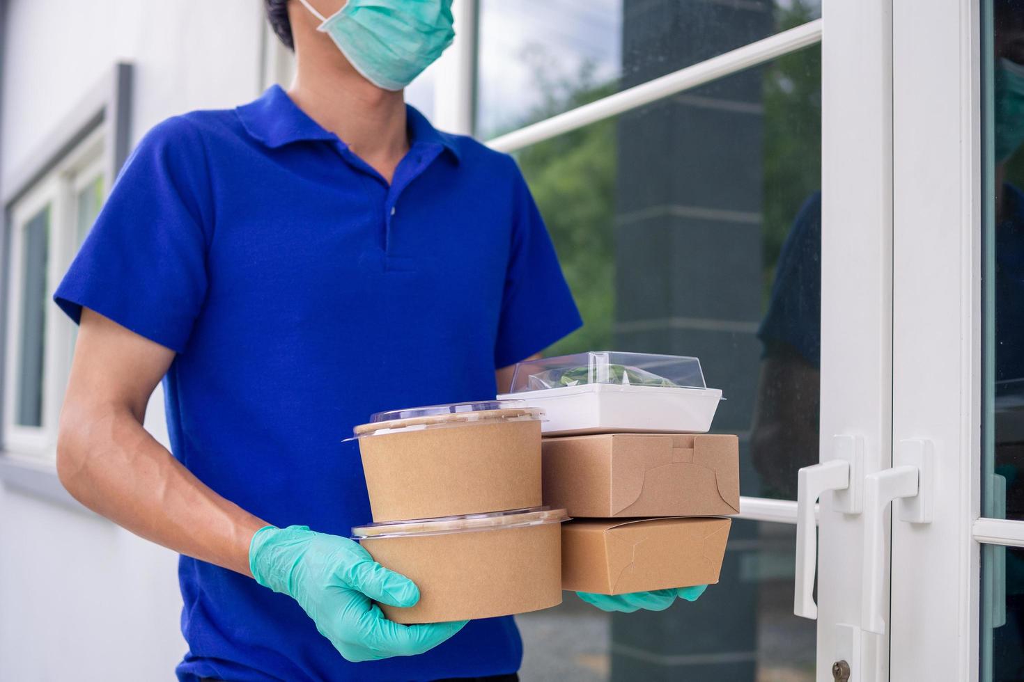 trabalhador de entrega de comida vestido com equipamento de proteção entrega almoço ao cliente foto