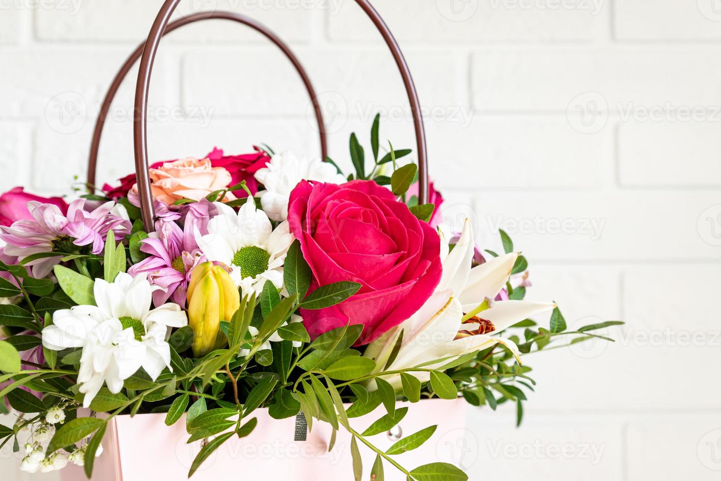 caixa rosa com buquê de flores em uma mesa. maravilhosa composição de flores violetas, vermelhas e brancas com vegetação é um presente perfeito para aniversário ou casamento foto
