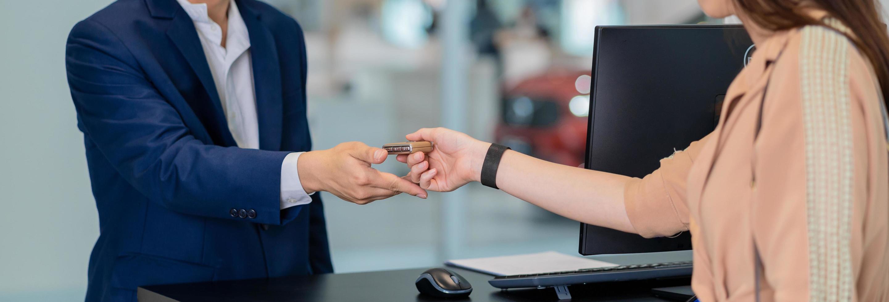 close de uma recepcionista asiática entregar as chaves do carro na concessionária de automóveis foto