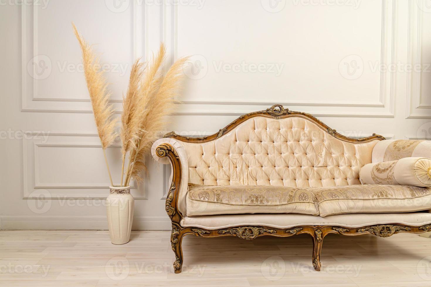 interior escandinavo elegante da sala de um apartamento moderno com grama de pampas e um sofá aconchegante em cores claras. um pedaço de sofá clássico bege e grama dos pampas em um vaso. grama dos pampas. decoração de casa foto