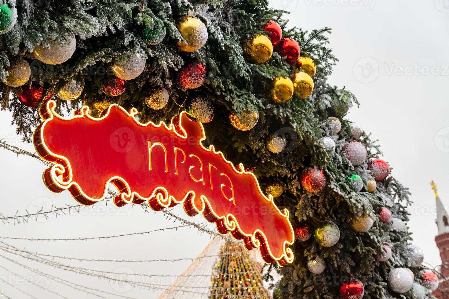 arco de natal decorado com enfeites e neve. tabuleta vermelha com palavra em praga russa. projeto temporadas de moscou foto