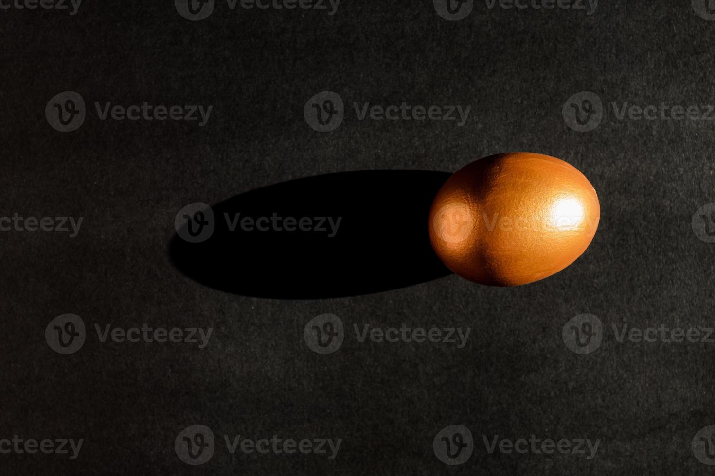 conceito de páscoa. um ovo de ouro sobre fundo preto com luz de sombra. vista superior com espaço de cópia foto