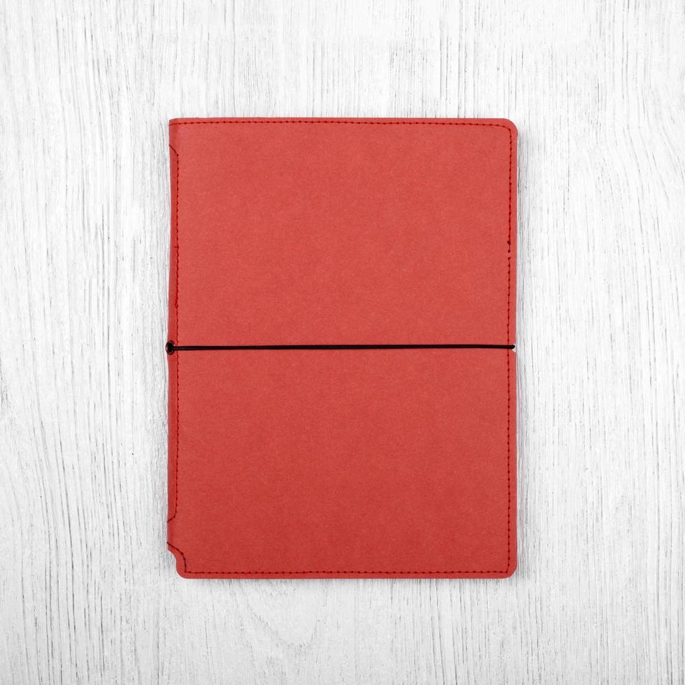 caderno vermelho na mesa de madeira branca, vista superior foto