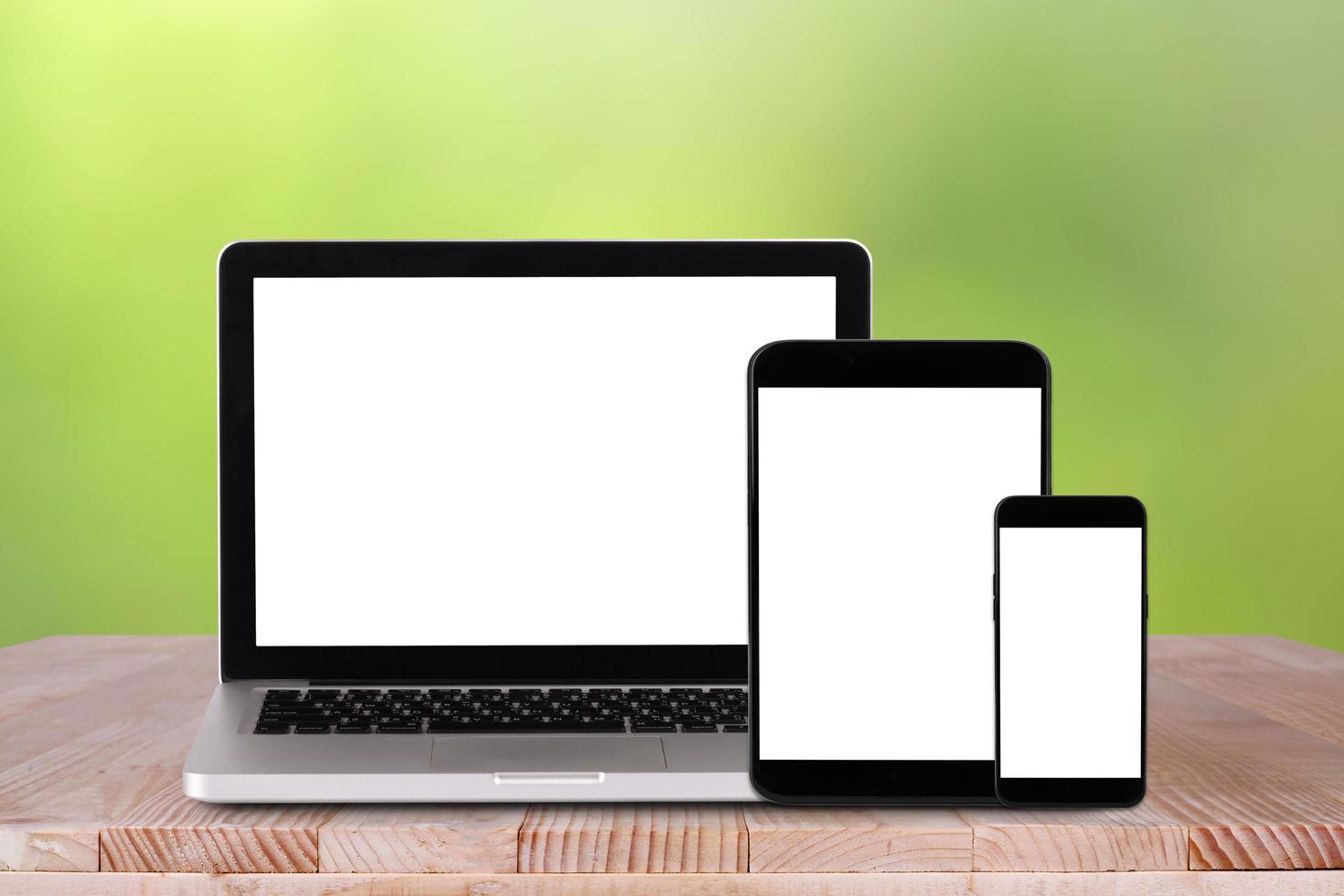 vista frontal do laptop, tablet pc, smartphone está na mesa de trabalho com fundo verde bokeh foto