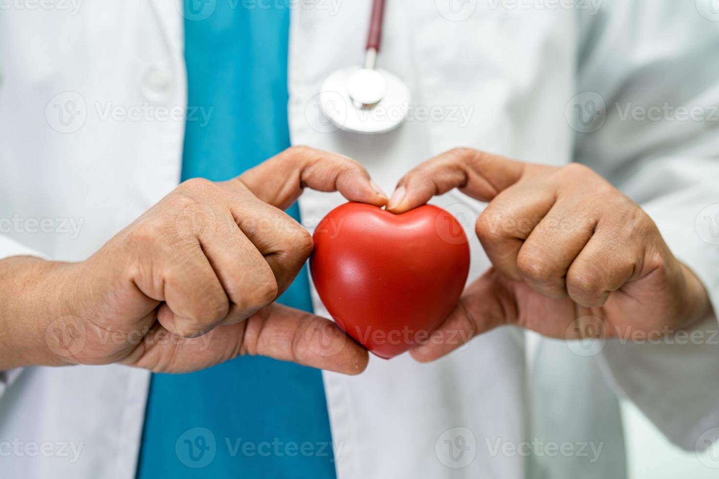 médico segurando um coração vermelho na enfermaria do hospital, conceito médico forte e saudável. foto