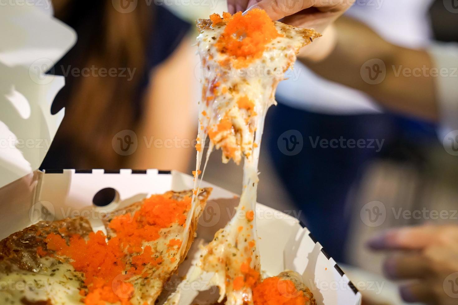 a mão da mulher tira pedaços de pizza do prato de pizza no evento do foodtruck, a pizza do queijo é esticada por ela. foto