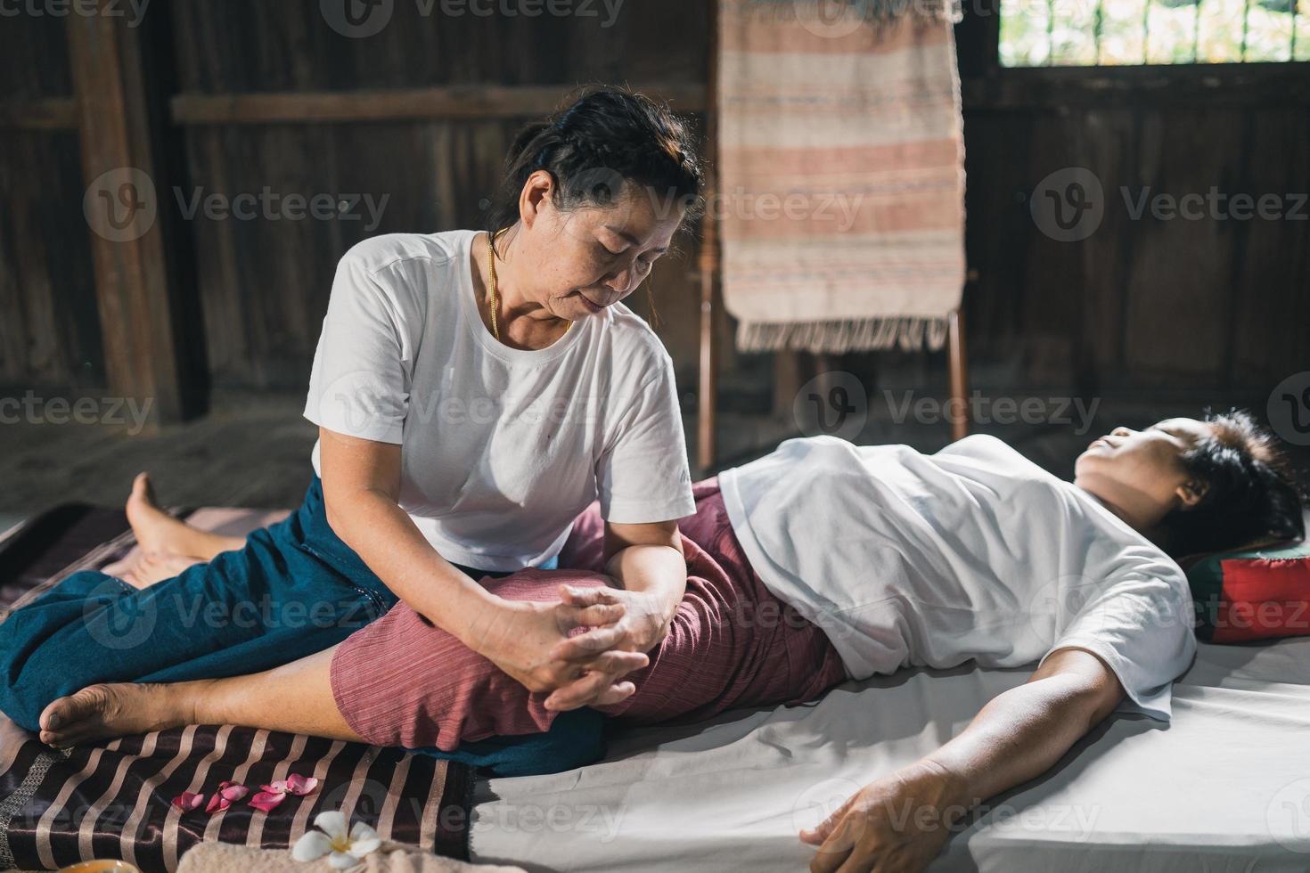 massagem e spa tratamento relaxante do estilo tradicional de massagem tailandesa da síndrome do escritório. asain massagista feminina sênior fazendo massagem tratar a mão, dor nas costas, dor no braço, pé e estresse para velha cansada. foto