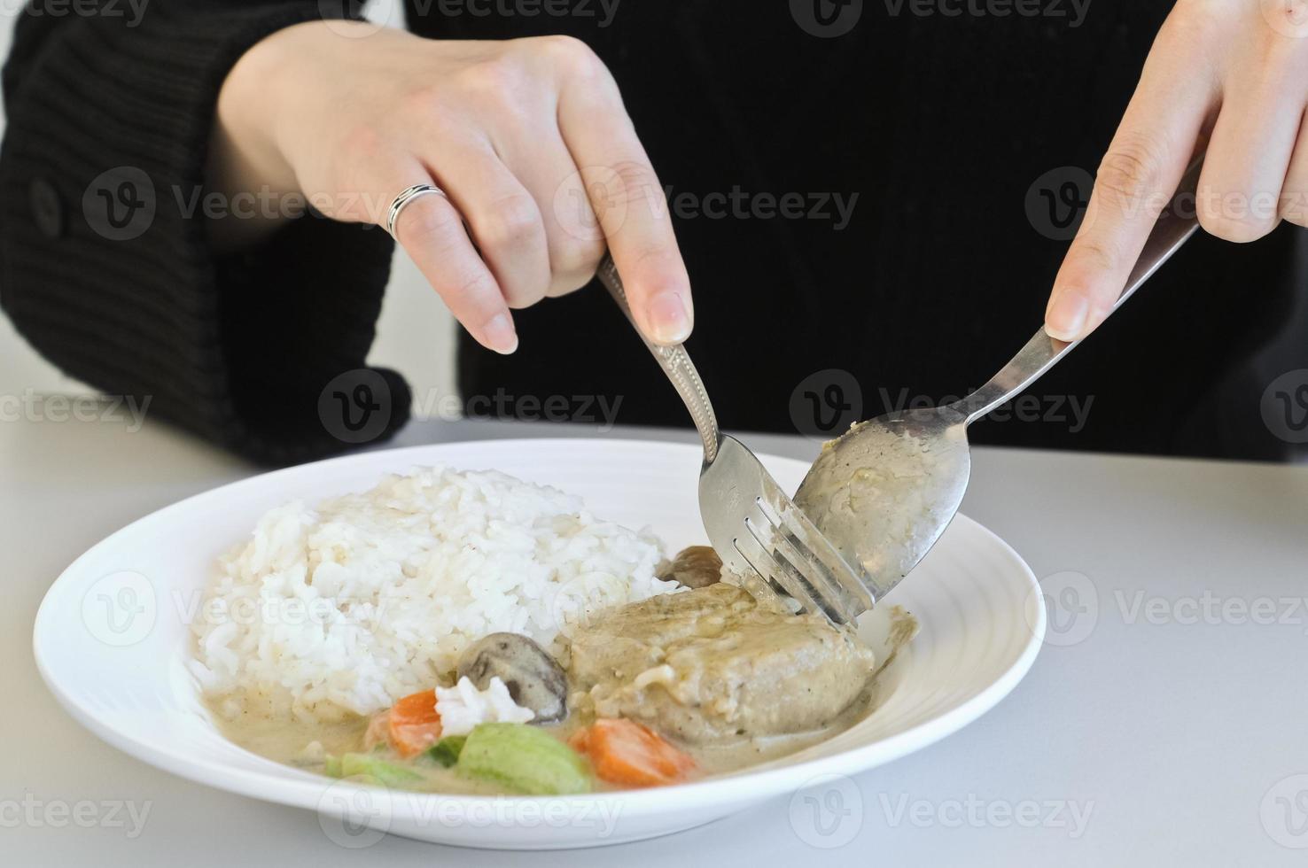 uma senhora comendo arroz de curry com colher e garfo foto