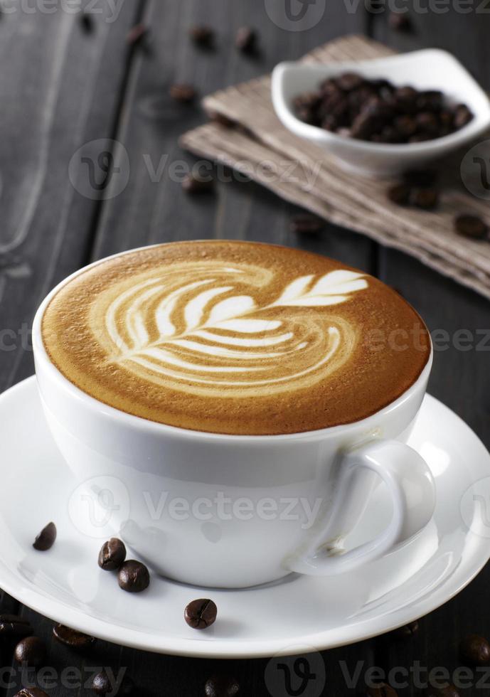 xícara de café e Pires em uma mesa de madeira. fundo escuro foto