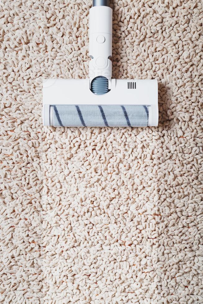 a escova turbo de um aspirador sem fio limpa o tapete da casa com uma faixa limpa foto