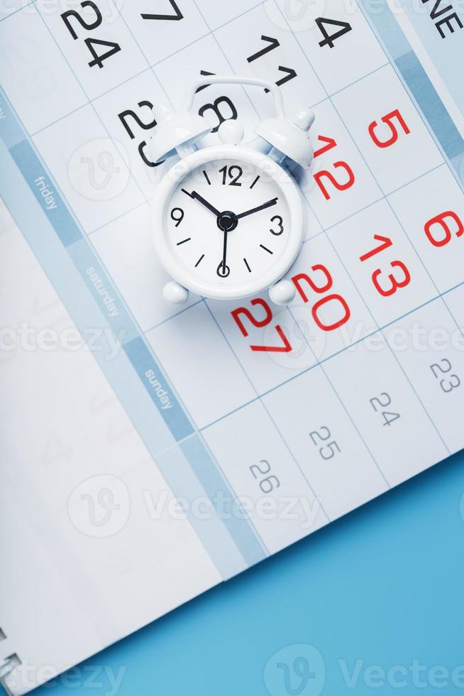 calendário anual com um despertador branco em um fundo azul foto