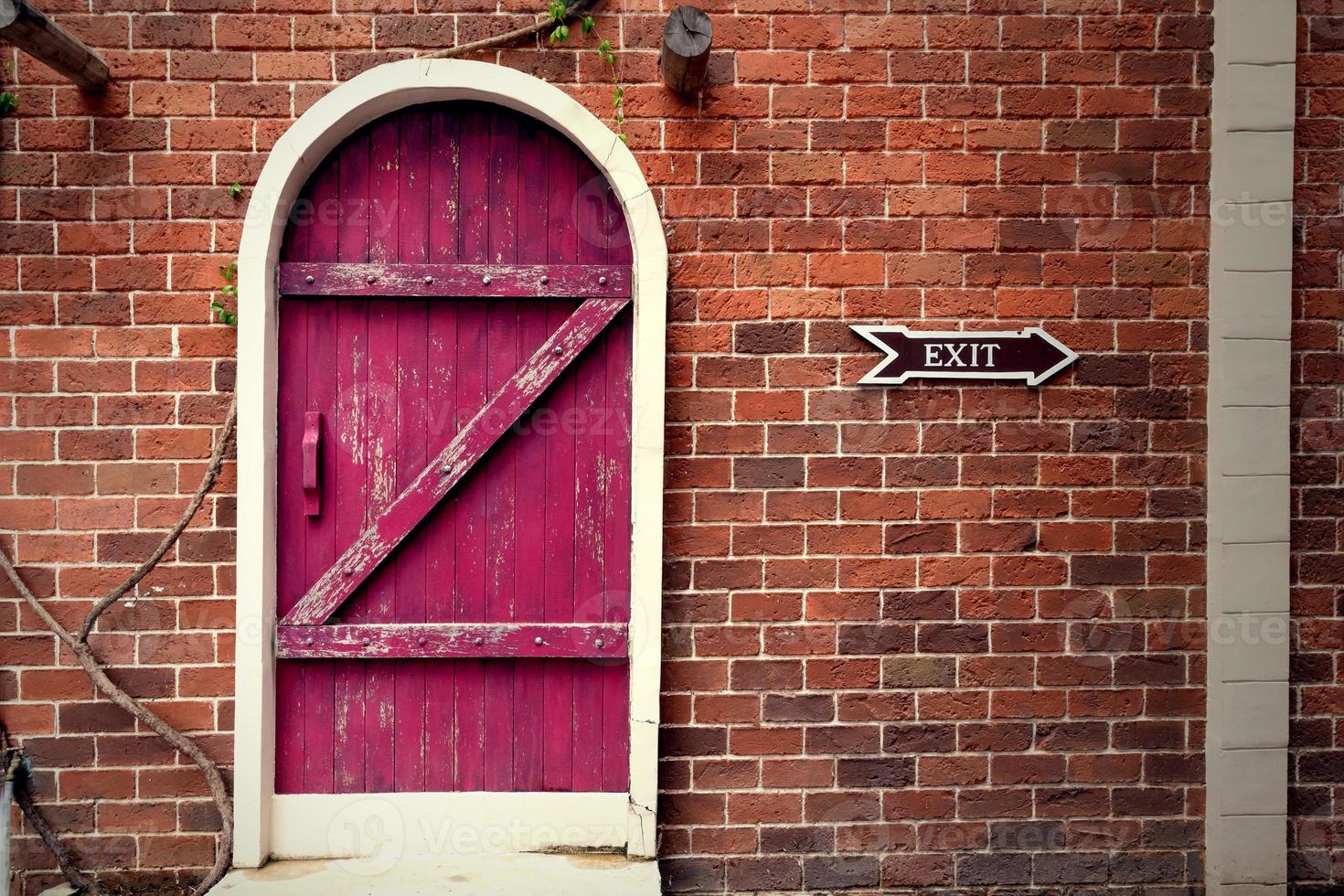 porta de madeira vintage vermelha na parede de tijolo marrom foto