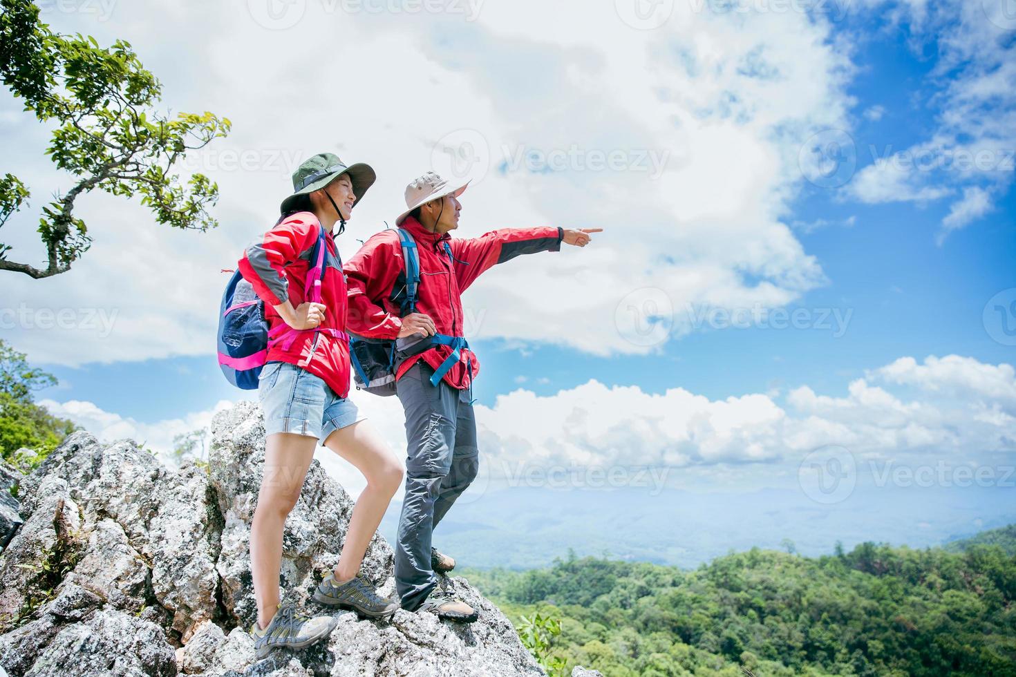 casal de jovem turista assistindo espetaculares paisagens montanhosas em altas montanhas. homem e mulher alpinista no topo da rocha. um casal de viajantes apaixonados. as pessoas saúdam o amanhecer. amantes viajam. espaço de cópia foto