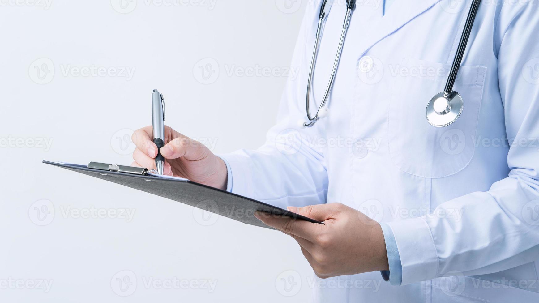 médico com estetoscópio no jaleco branco segurando a prancheta, escrevendo diagnóstico de registro médico, isolado no fundo branco, close-up, vista recortada. foto