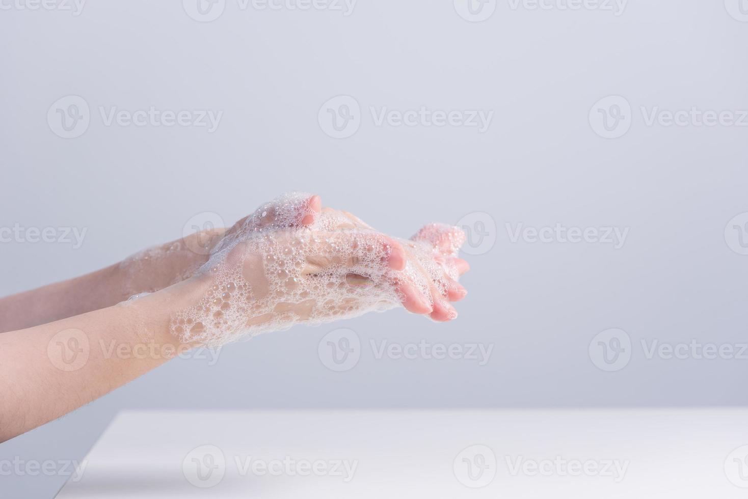 Lavando as mãos. jovem asiática usando sabão líquido para lavar as mãos, conceito de higiene para proteger o coronavírus pandêmico isolado em fundo branco cinza, close-up. foto