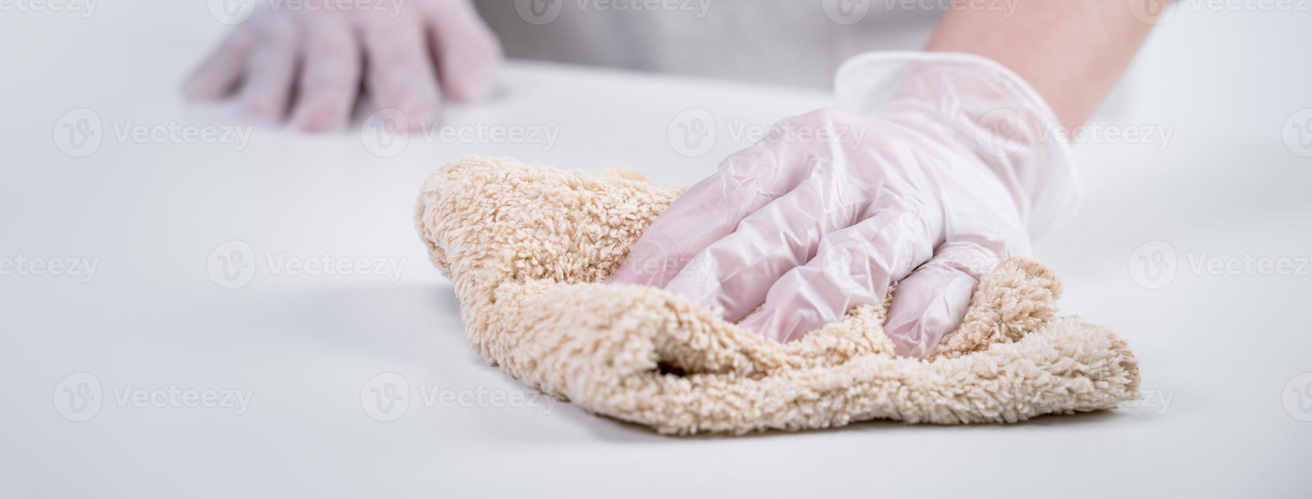 jovem dona de casa está limpando, limpando a superfície da mesa em casa para impedir a propagação da infecção com pano molhado, antibacteriano, close-up, estilo de vida. foto