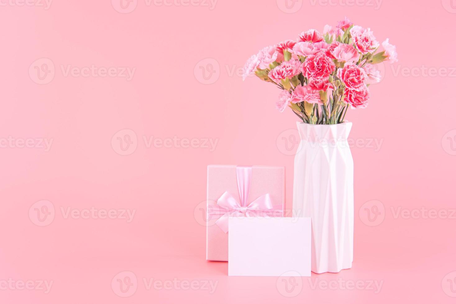 conceito de design de presente de feriado do dia das mães, buquê de flores de cravo rosa com cartão, isolado em fundo rosa claro, espaço de cópia. foto