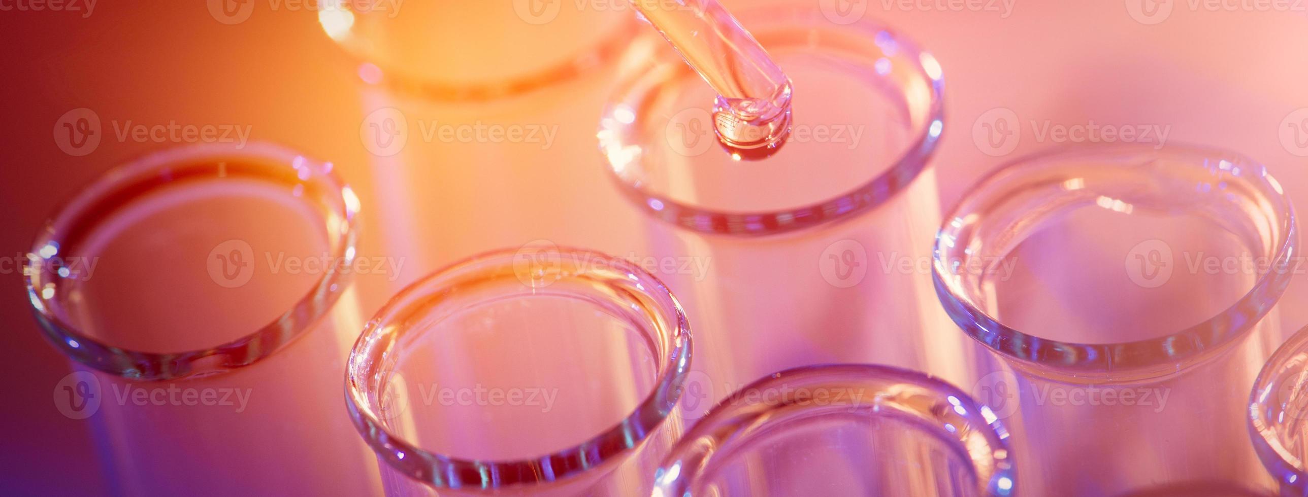 fileira de tubos de ensaio. conceito de laboratório médico ou de ciências, gota líquida com conta-gotas em fundo de tom azul, close-up, imagem de microfotografia. foto
