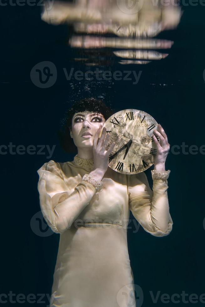 mulher assustadora com relógio nas mãos em véu preto debaixo d'água foto