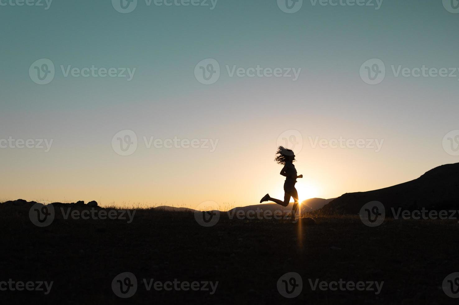 garota corre ao pôr do sol nas montanhas. foto