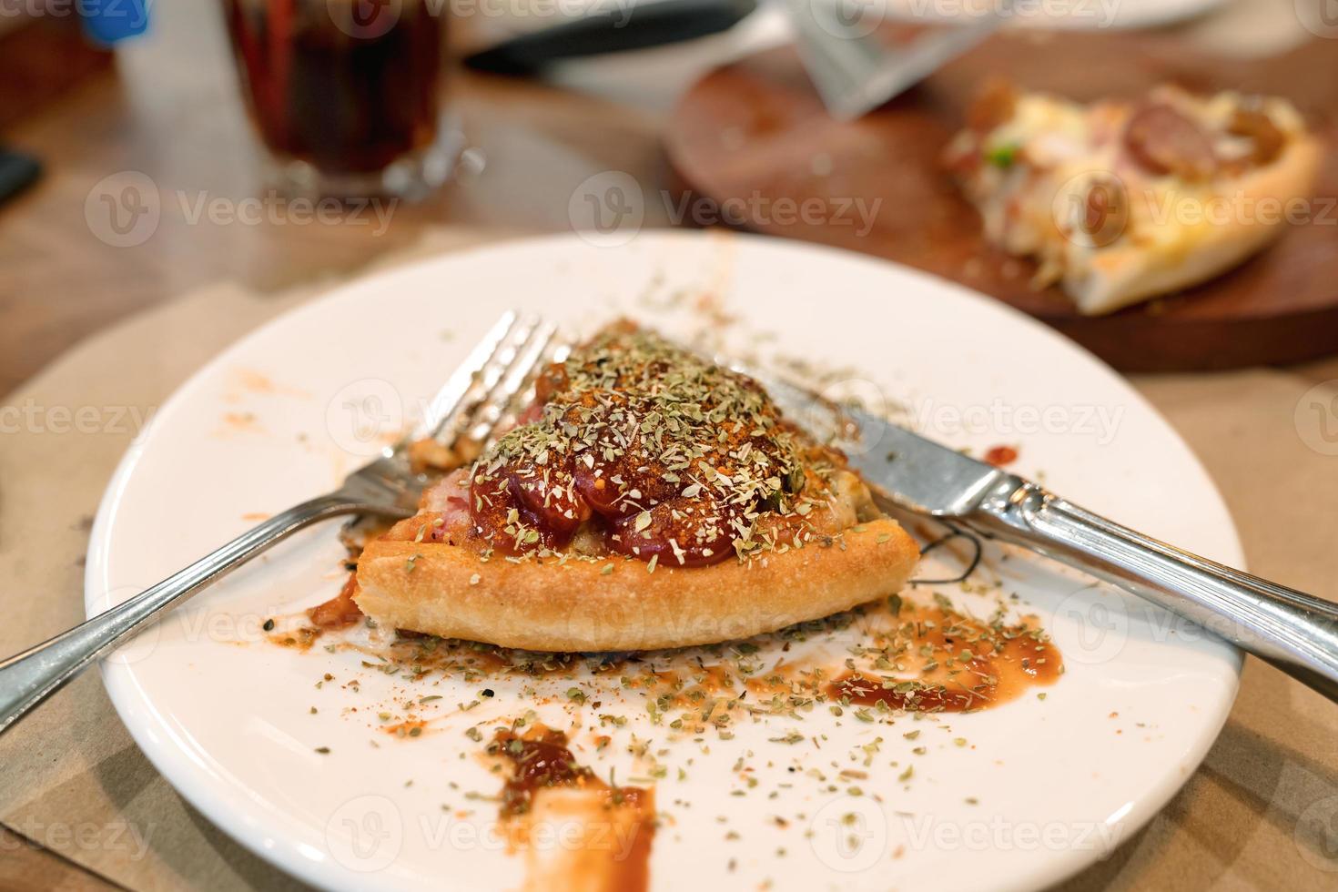 pedaço de pizza no prato branco com garfo e faca foto