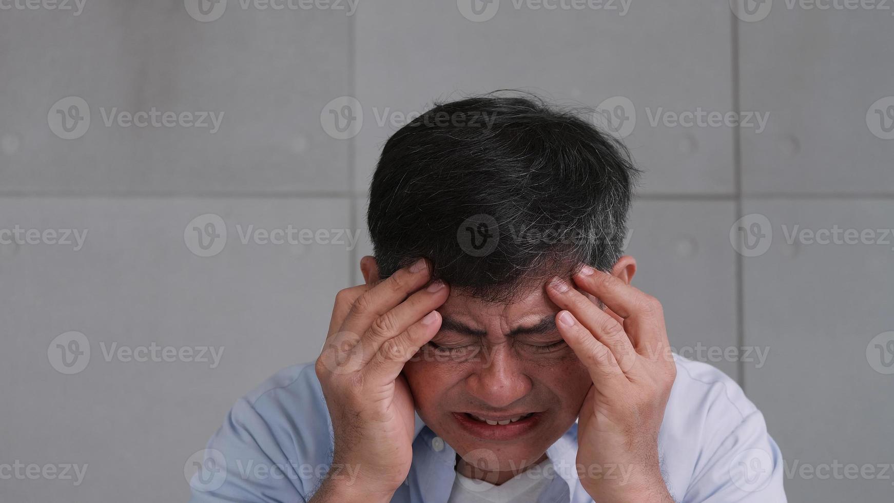 velho asiático com enxaqueca. homem se sente estressado e preocupado com problemas de saúde. foto
