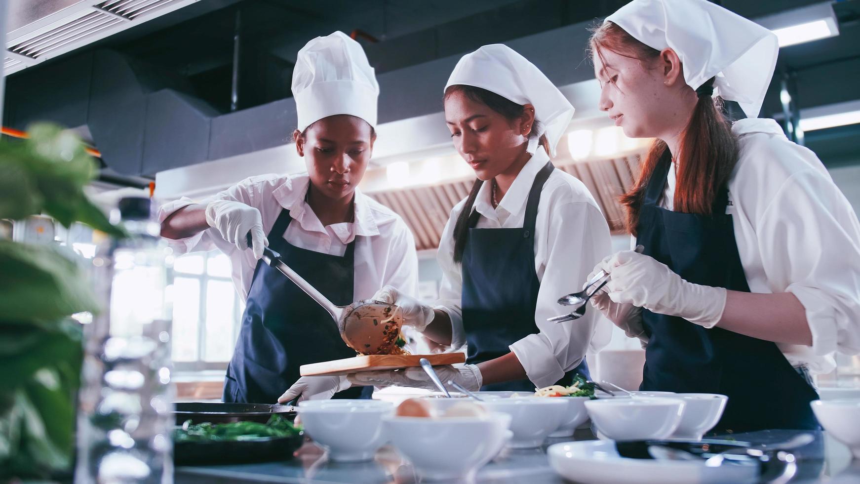 grupo de alunas se divertindo aprendendo a cozinhar. estudantes do sexo feminino em uma aula de culinária. foto