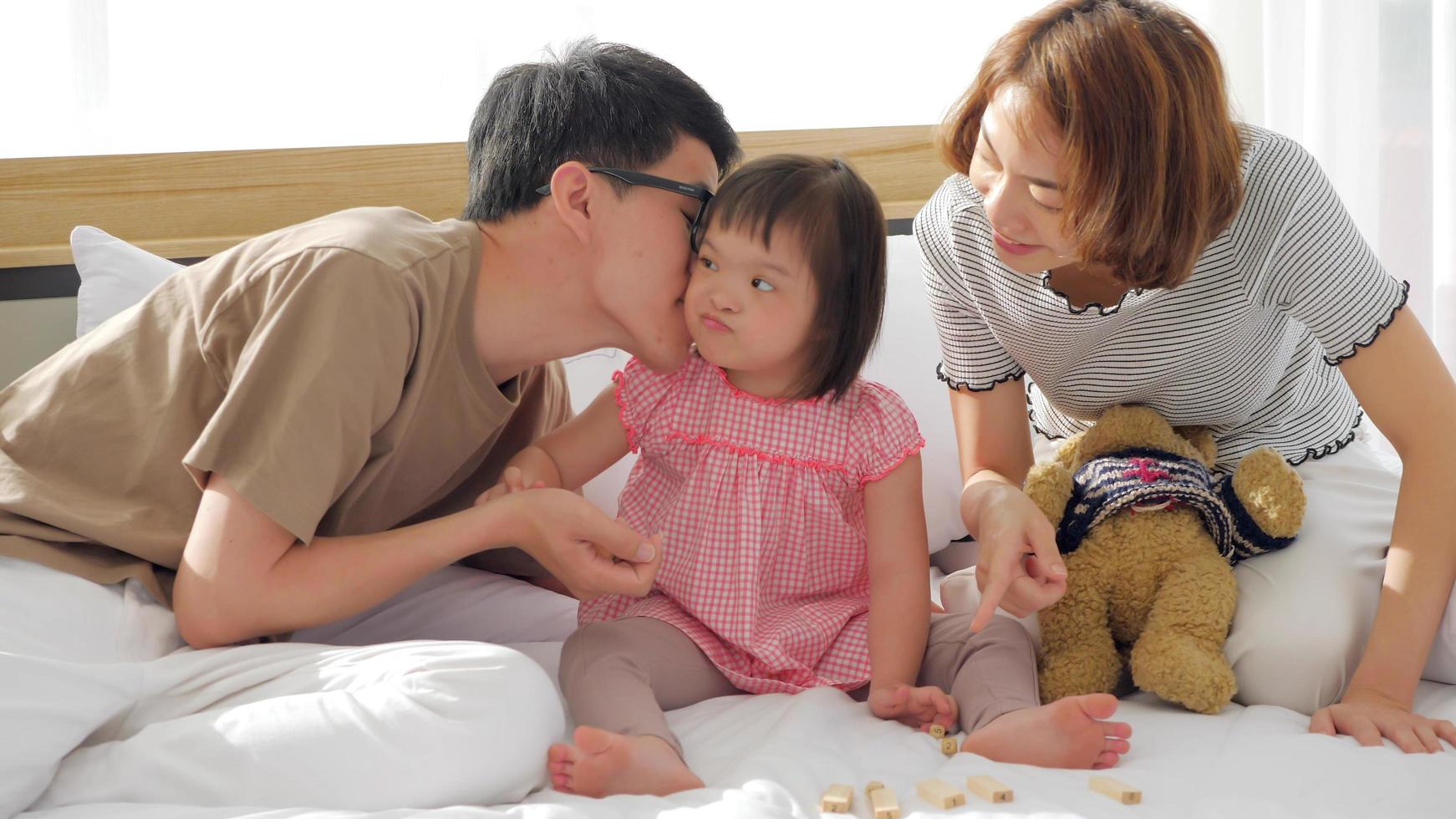 família feliz com mãe, pai e filha com deficiência passando tempo juntos no quarto. foto