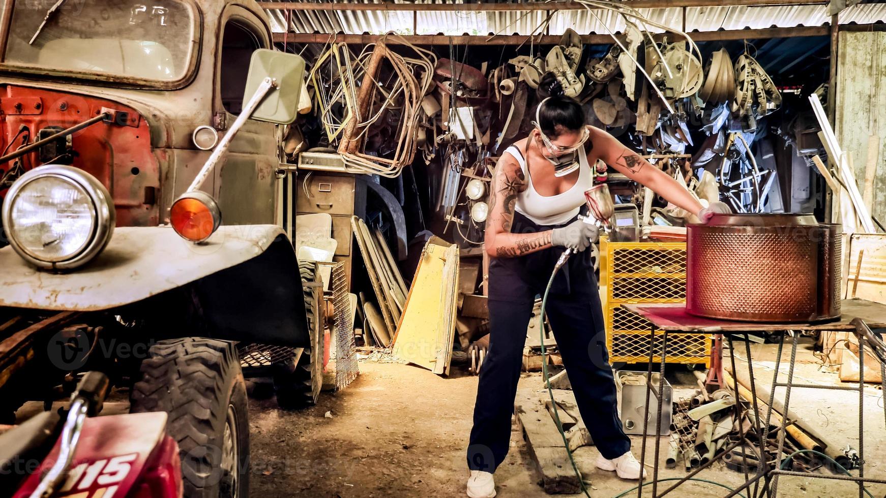 trabalhador mecânico jovem atraente reparando um carro antigo na garagem velha. foto