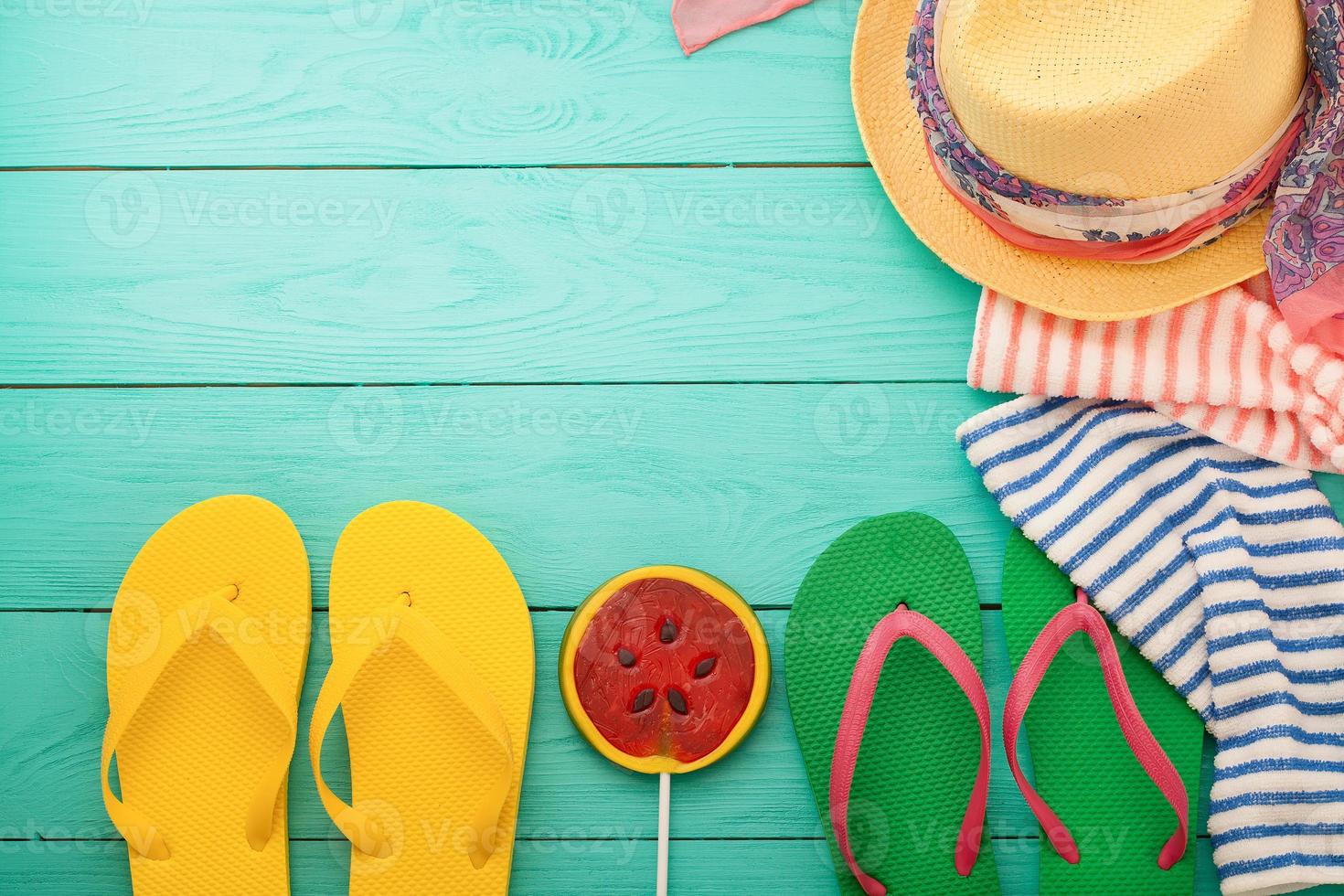férias na praia. chinelos, doces de melancia, chapéu, toalhas. acessórios de verão e espaço de cópia em fundo azul de madeira. vista do topo foto