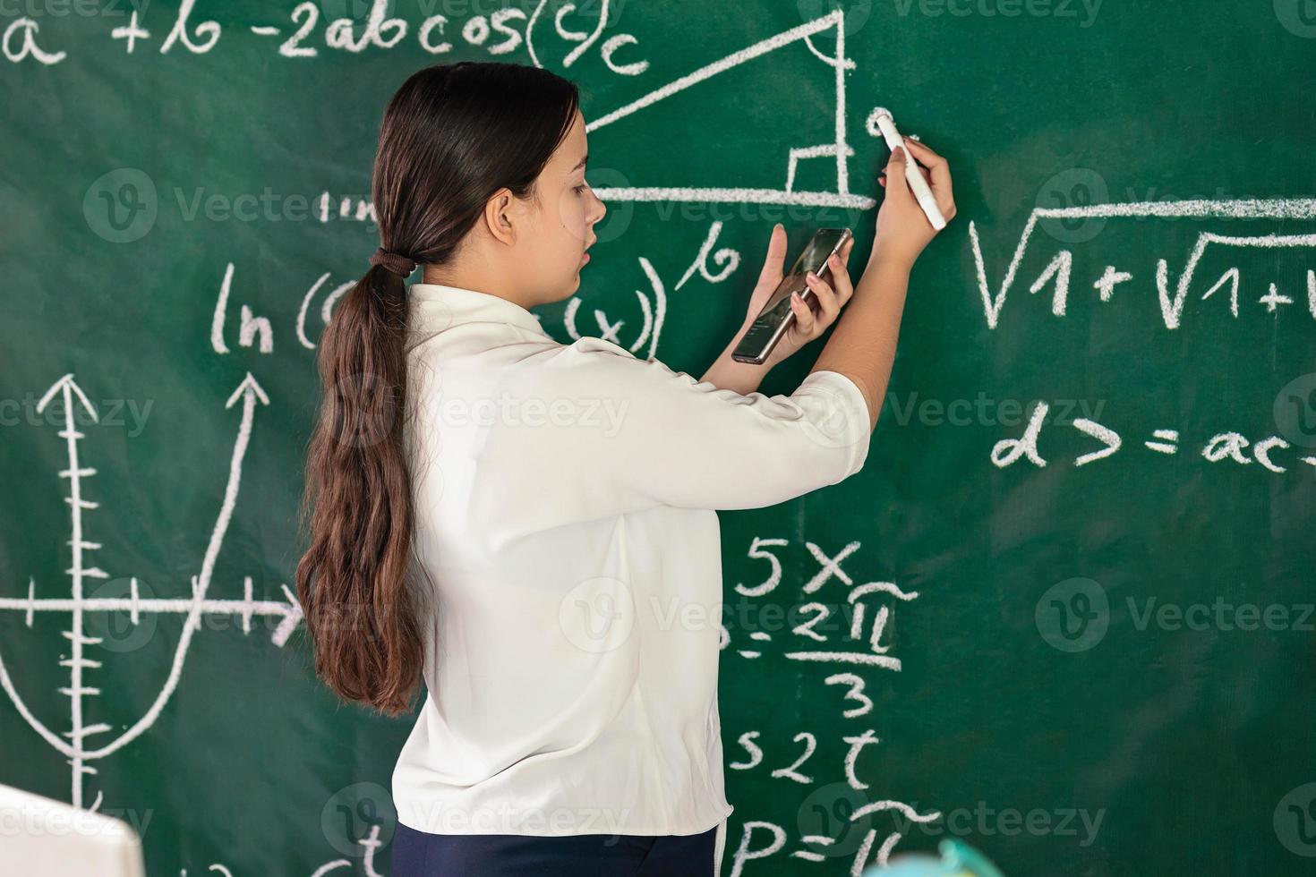 garota escreve exemplos matemáticos no conselho escolar. resolve um problema de geometria. foto